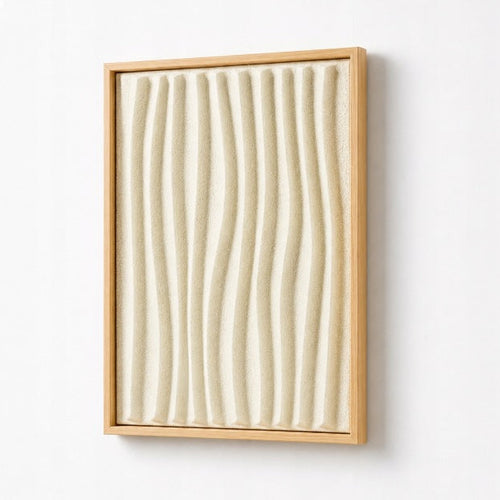 A framed abstract wall art piece featuring vertical wavy ridges in a warm cream or off-white tone, enclosed in a light natural wood frame and mounted on a plain white wall.